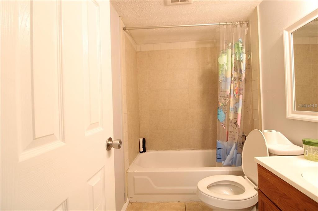 A bathroom features a tiled shower-tub combination, a toilet, and a vanity with a mirror — 311 SCOTTSDALE SQUARE UNIT 311, WINTER PARK, FL