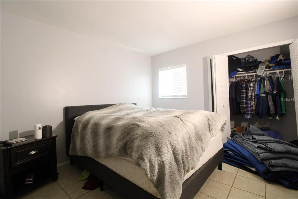 A bedroom features a bed with a gray faux fur blanket, tile flooring, and a closet — 311 SCOTTSDALE SQUARE UNIT 311, WINTER PARK, FL