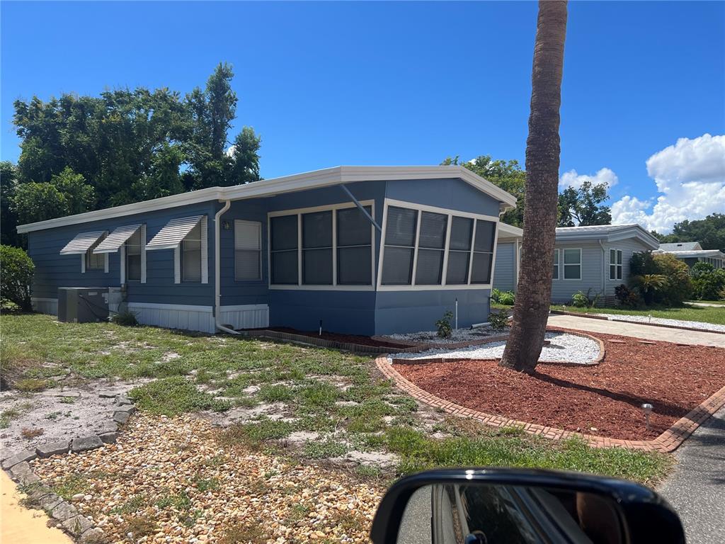 A blue mobile home with a screened-in porch sits on a lot with landscaping — 212 PARADISE S, LEESBURG, FL