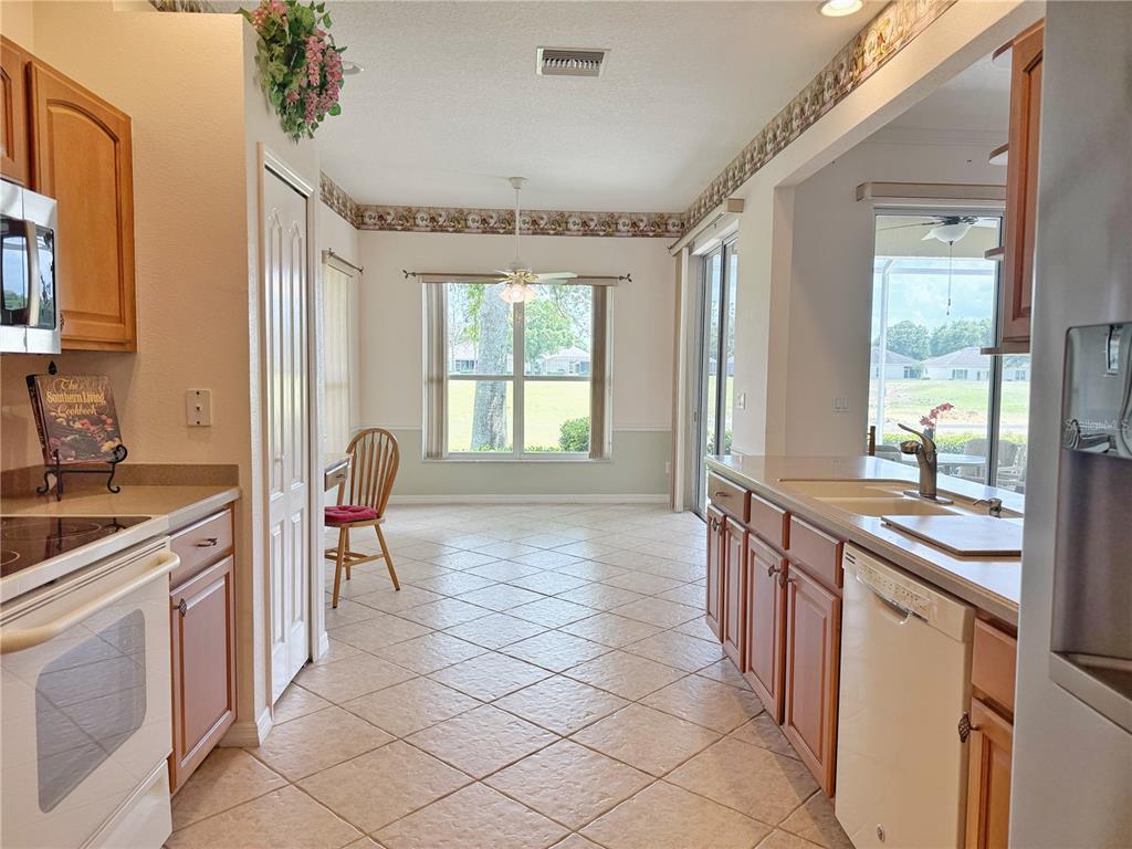 A kitchen with wood cabinets, tile floors, and a dining area overlooking a backyard — 3445 CAPLAND AVENUE, CLERMONT, FL