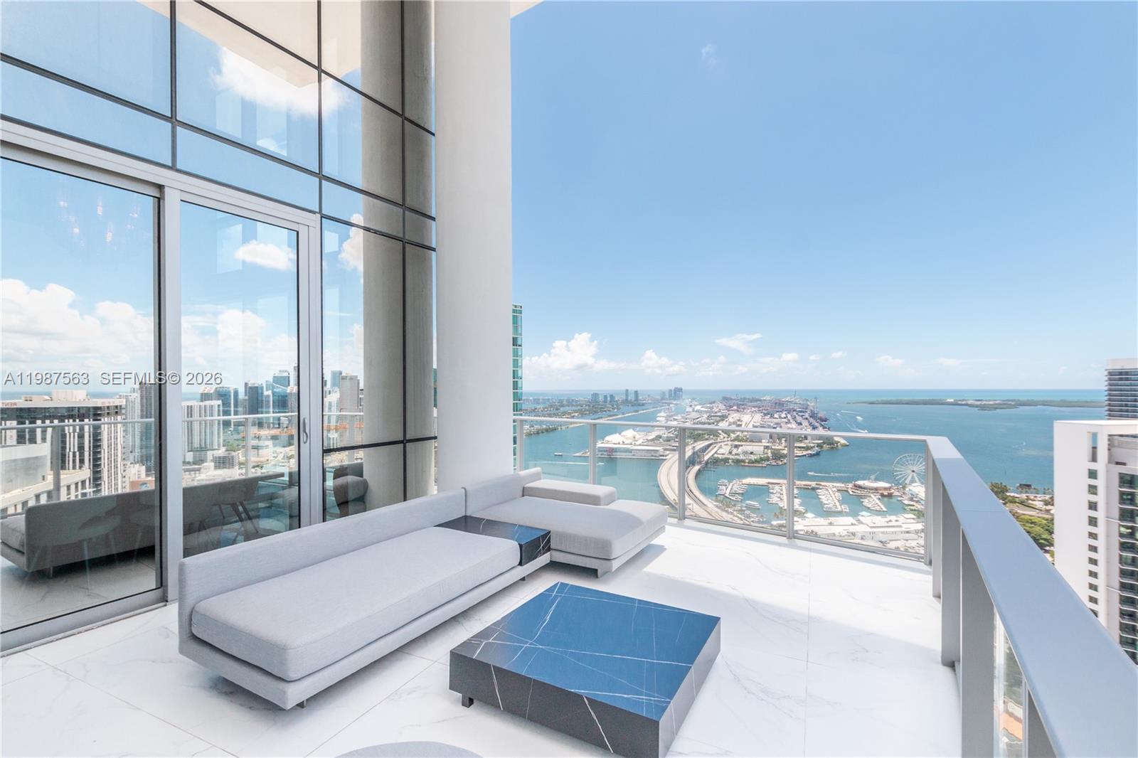 A modern balcony features a grey sectional sofa, a marble coffee table, and harbor views — 851 NE 1st Ave # 4611, Miami FL 33132, MIAMI, FL