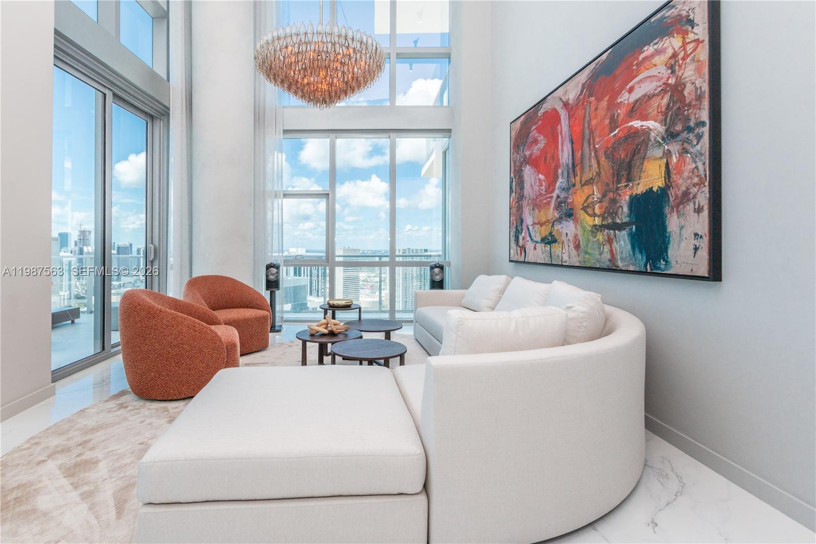 A living room with a curved white sofa, orange chairs, and a large abstract painting — 851 NE 1st Ave # 4611, Miami FL 33132, MIAMI, FL