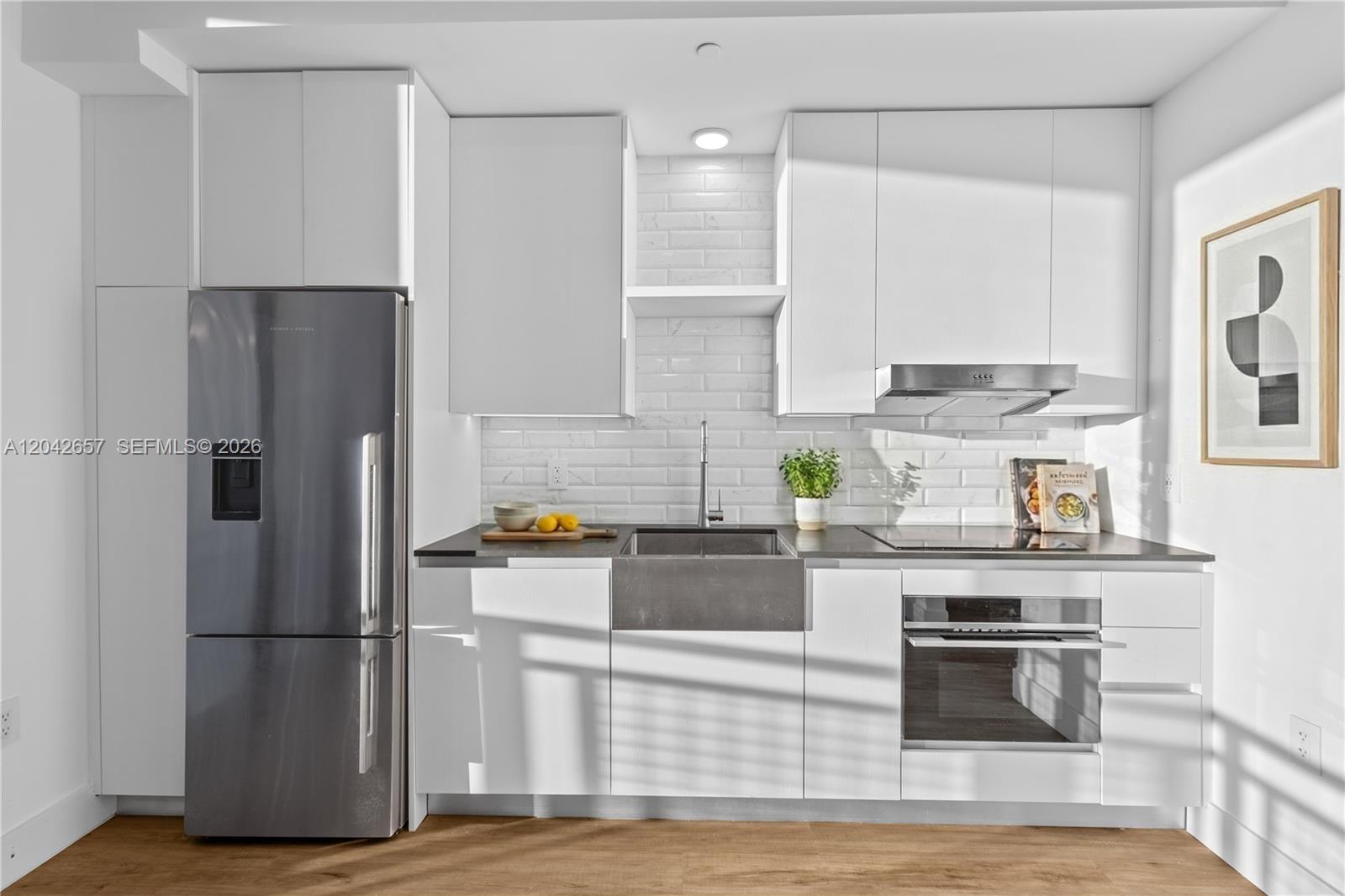 A modern kitchen features white cabinetry, a stainless steel refrigerator, and a farmhouse sink — 650 NE 2nd Ave # 3412, Miami FL 33132, MIAMI, FL