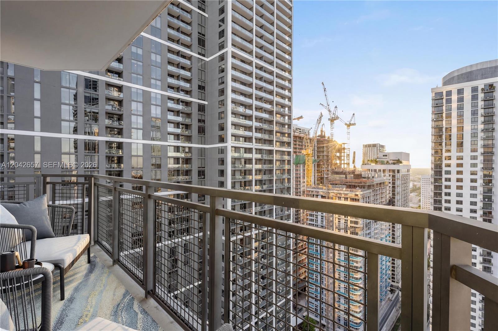 A balcony with outdoor seating overlooks a dense urban skyline featuring several high-rise buildings — 650 NE 2nd Ave # 3412, Miami FL 33132, MIAMI, FL