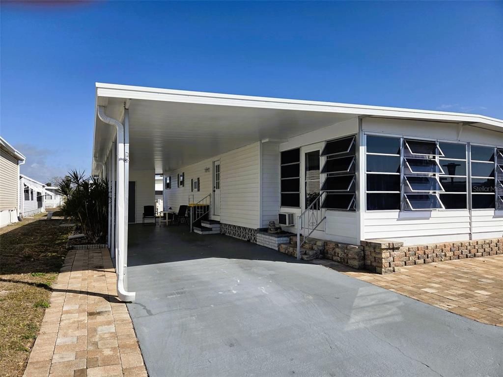 A white mobile home features a covered carport and a paved driveway — 3225 SWEET GUM TERRACE, SARASOTA, FL