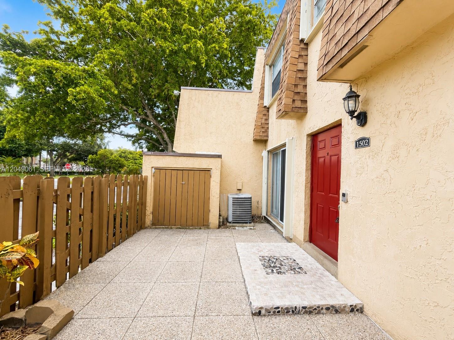 A patio with a red front door, a wooden fence, and an air conditioning unit — 3741 NW 95th Ter # 1502, Sunrise FL 33351, SUNRISE, FL