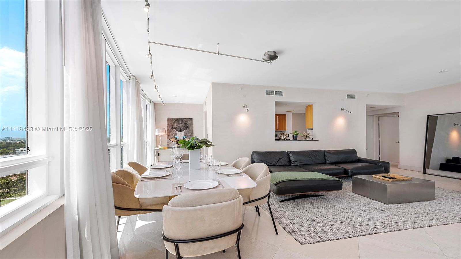 A modern living and dining area features a black leather sectional, white table, and floor-to-ceiling windows — 101 20th St # 2102, Miami Beach FL 33139, MIAMI BEACH, FL