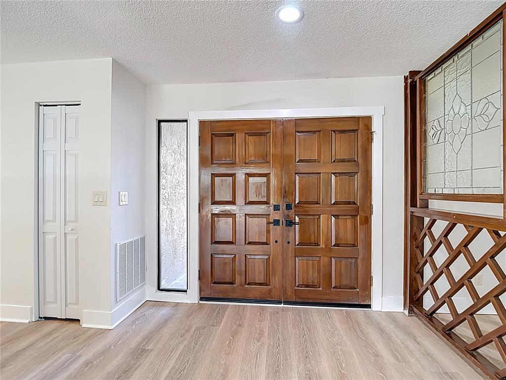 An entryway features double wooden doors, a side window, a closet, and a lattice screen — 4072 BELMOOR DRIVE, PALM HARBOR, FL