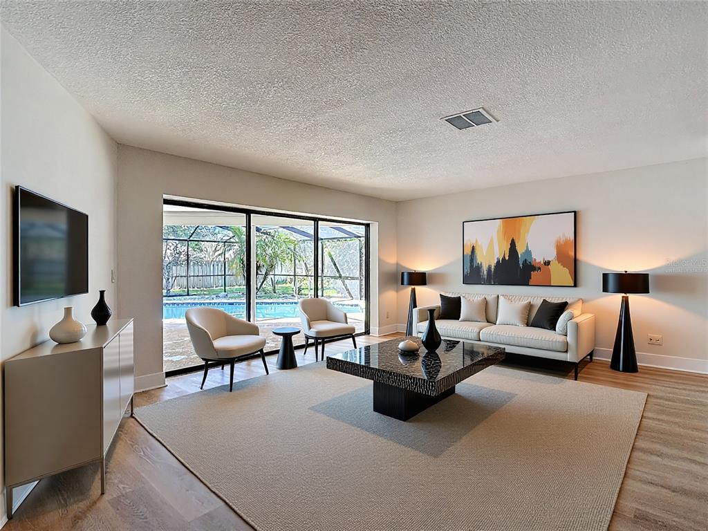 A living room features a sofa, two chairs, a coffee table, and sliding glass doors — 4072 BELMOOR DRIVE, PALM HARBOR, FL