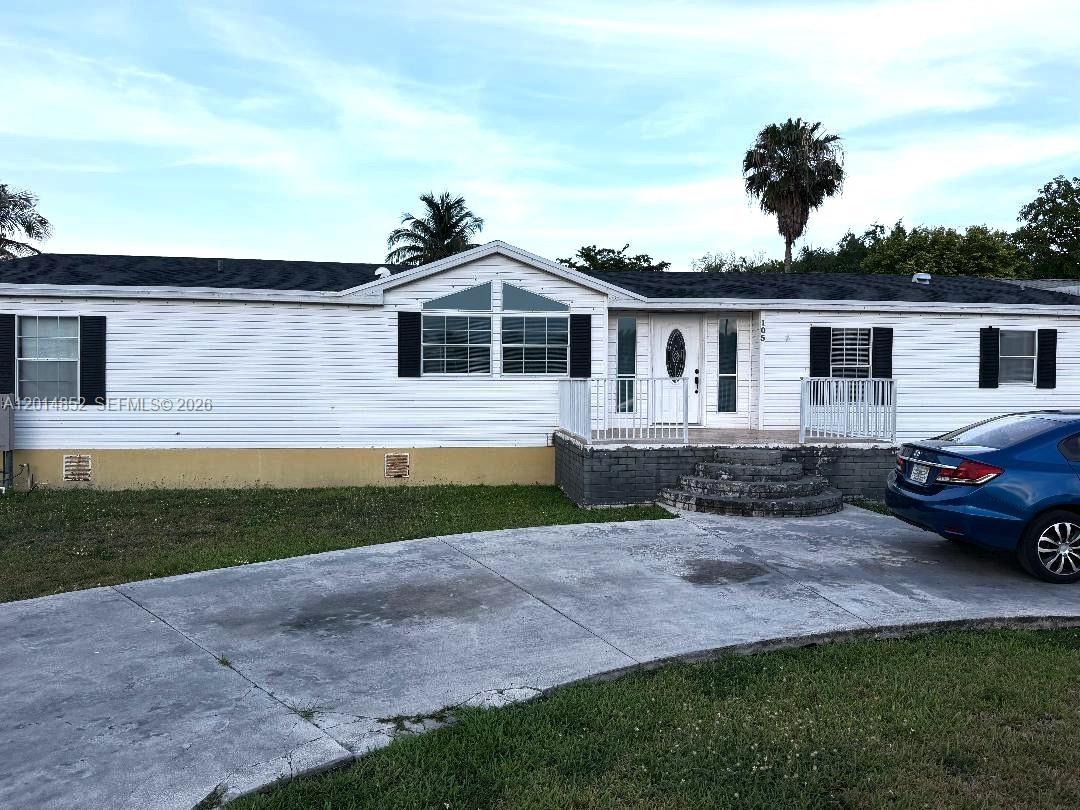 A single-story manufactured home with white siding, a dark roof, and a concrete driveway — 19800 SW 180th Ave unit 105, Miami FL 33187, MIAMI, FL
