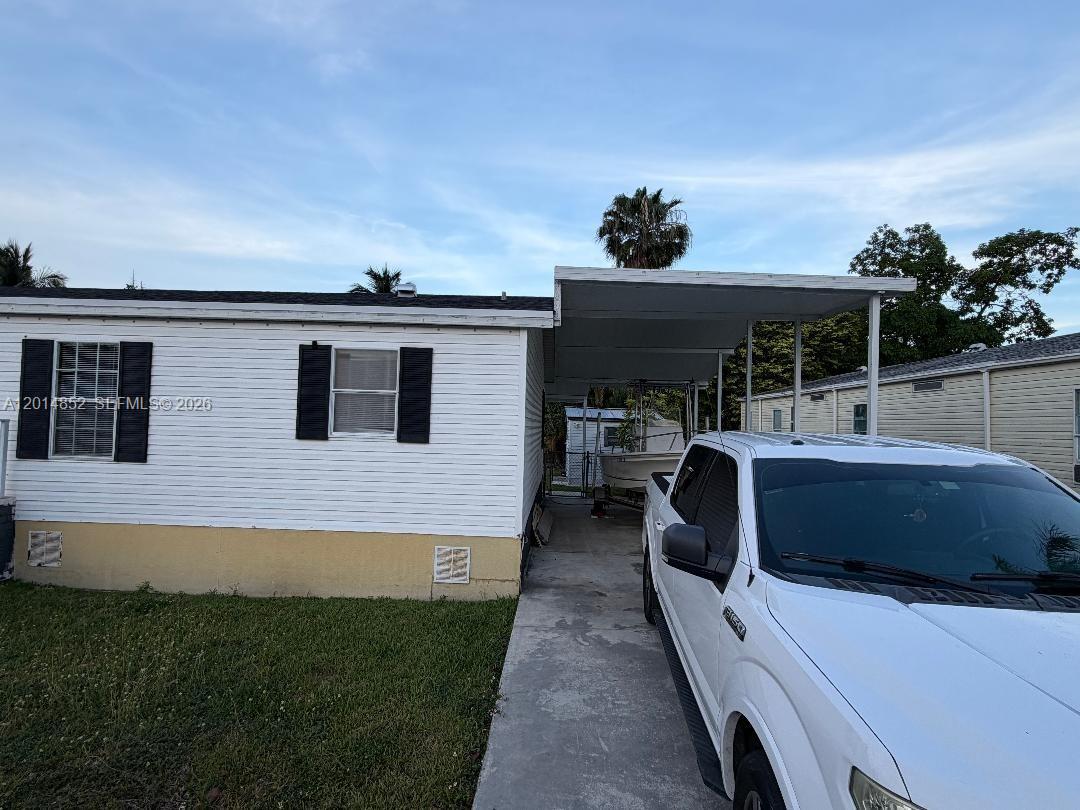 A white mobile home features a carport and a white pickup truck parked in front — 19800 SW 180th Ave unit 105, Miami FL 33187, MIAMI, FL
