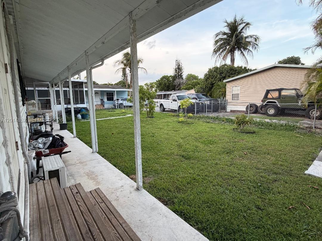 A covered concrete patio overlooks a grassy backyard with a fence and parked vehicles — 19800 SW 180th Ave unit 105, Miami FL 33187, MIAMI, FL