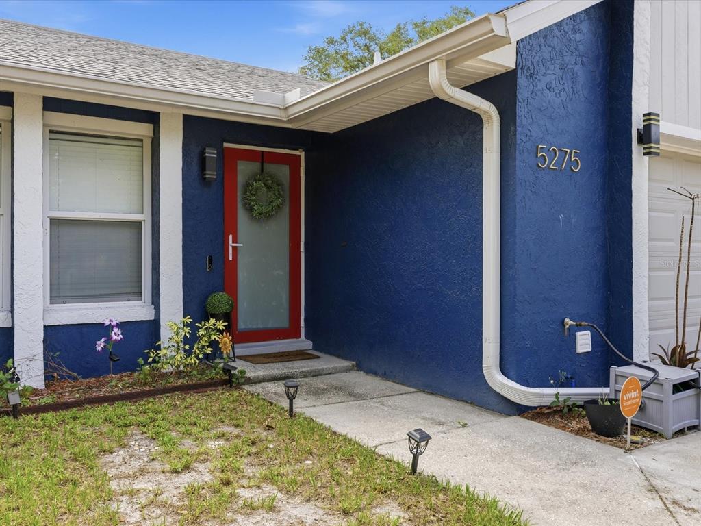 The exterior of a house features blue stucco walls, a red front door, and white trim — 5275 SIGNAL HILL ROAD, ORLANDO, FL