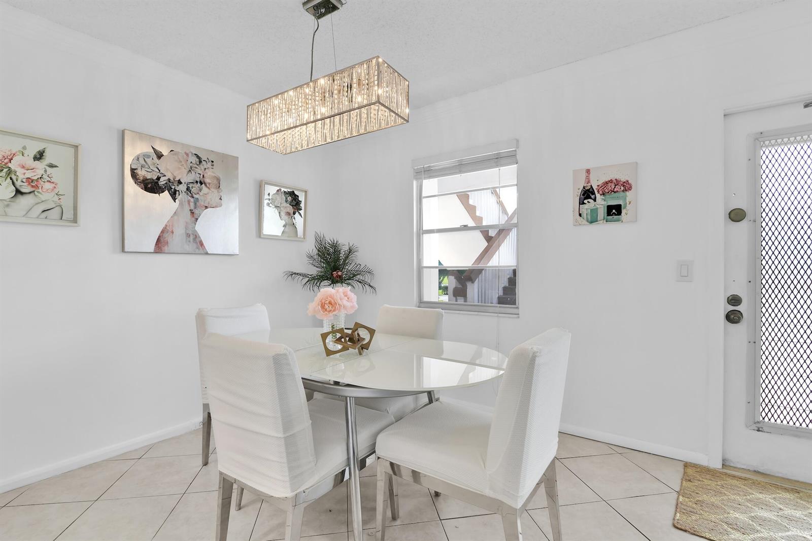 A dining area features a glass table, four white chairs, and a rectangular crystal chandelier — 2043 Cornwall C # 2043, Boca Raton FL 33434, BOCA RATON, FL