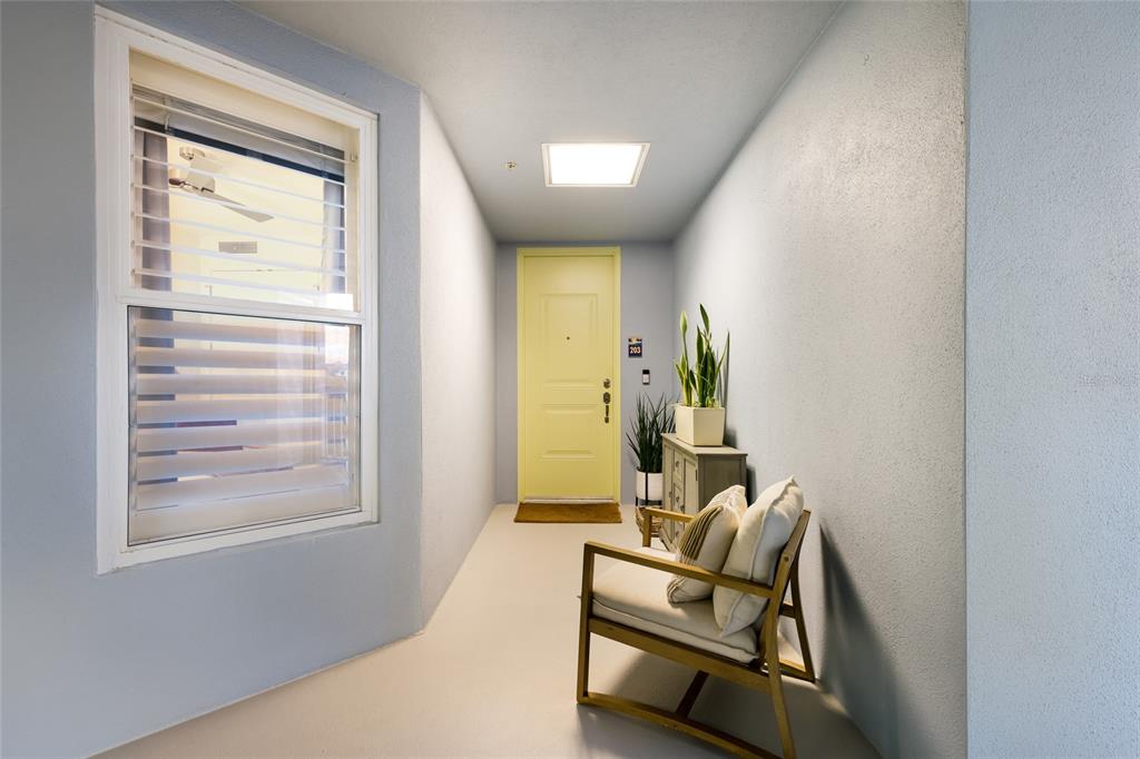 A light blue entryway features a yellow door, a wooden chair, and a small console — 376 ARUBA CIRCLE UNIT 203, BRADENTON, FL