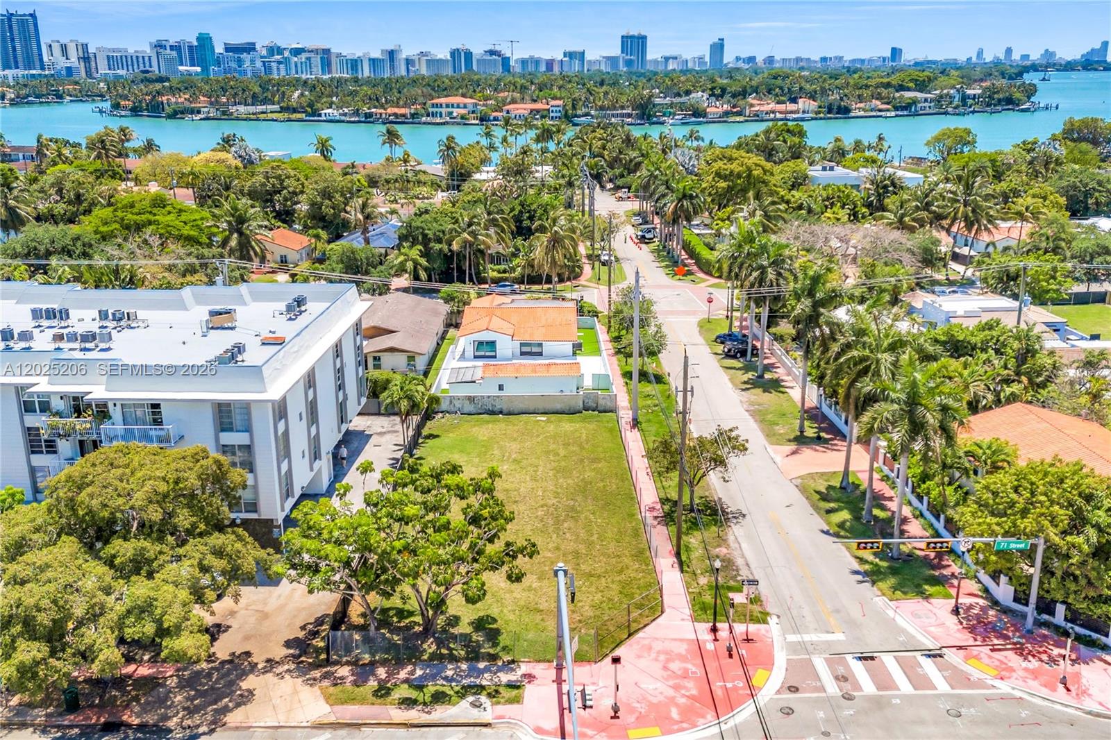 An aerial view shows a vacant lot next to a white apartment building near a street — 1240 71st St, Miami Beach FL 33141, MIAMI BEACH, FL