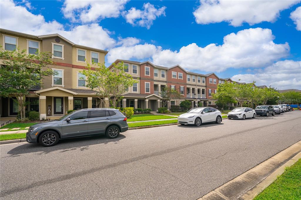 A row of multi-story townhouses with parked cars along the street under a cloudy sky — 10061 TOWN LAKE DRIVE, ORLANDO, FL