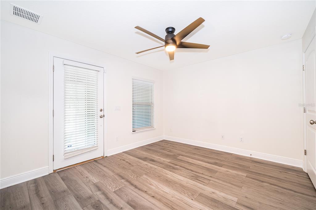 An empty room features light walls, wood-look flooring, a ceiling fan, and a glass-paneled door — 10061 TOWN LAKE DRIVE, ORLANDO, FL