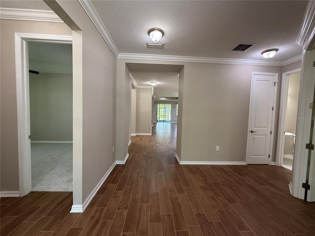 A hallway with wood-look tile flooring leads to an open living area with sliding doors — 12200 RANGELAND BOULEVARD, ODESSA, FL