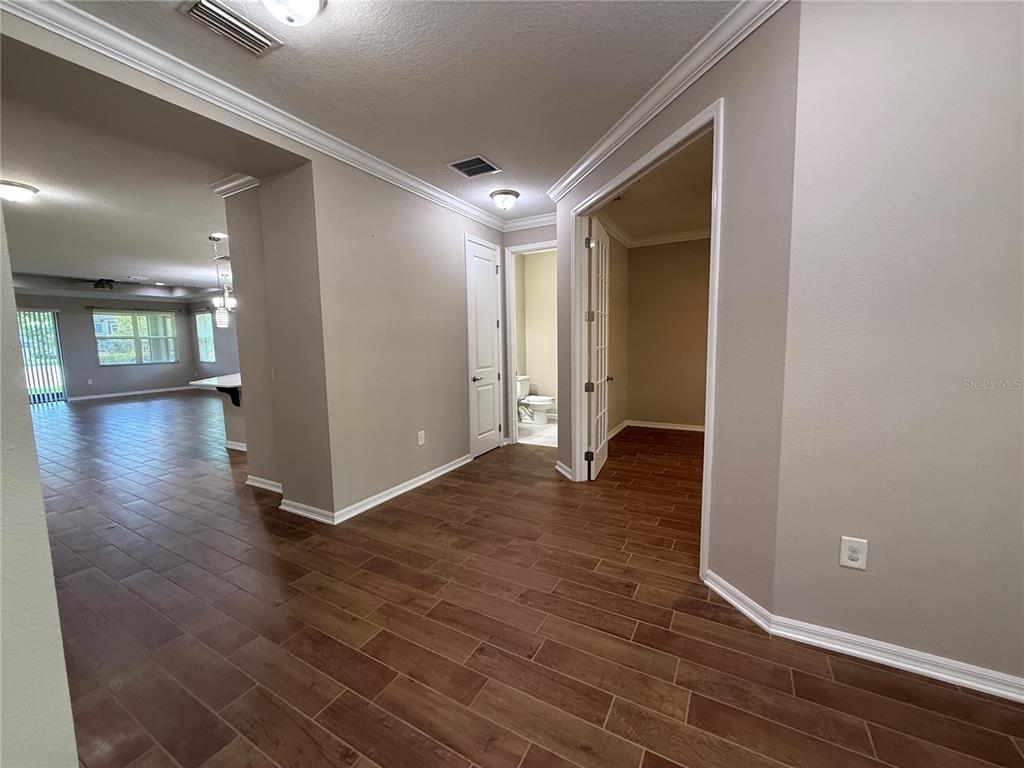 A hallway with wood-look tile flooring leads to a bathroom and a room with doors — 12200 RANGELAND BOULEVARD, ODESSA, FL