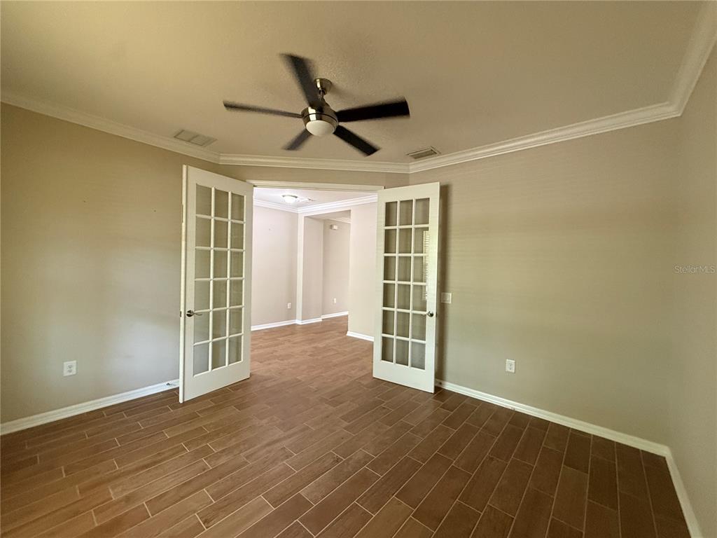 A room with wood-look tile flooring, a ceiling fan, and open French doors — 12200 RANGELAND BOULEVARD, ODESSA, FL