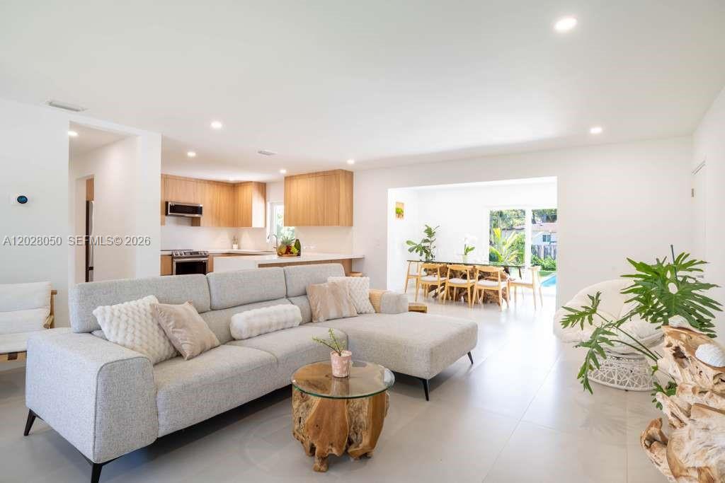 A bright living room features a light gray sectional sofa, wood-base coffee table, and kitchen — 13800 NE 1st Ave, Miami FL 33161, MIAMI, FL