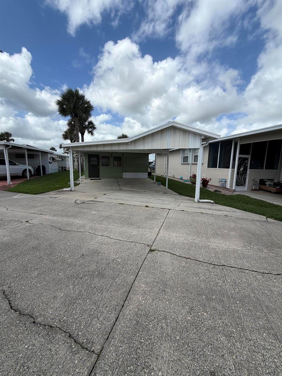 A mobile home features a concrete driveway, a covered carport, and a green exterior wall — 6511 SE 56th Street, Okeechobee FL 34974, OKEECHOBEE, FL