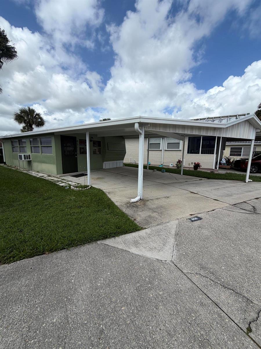 A single-story mobile home with a green exterior, a carport, and a concrete driveway — 6511 SE 56th Street, Okeechobee FL 34974, OKEECHOBEE, FL