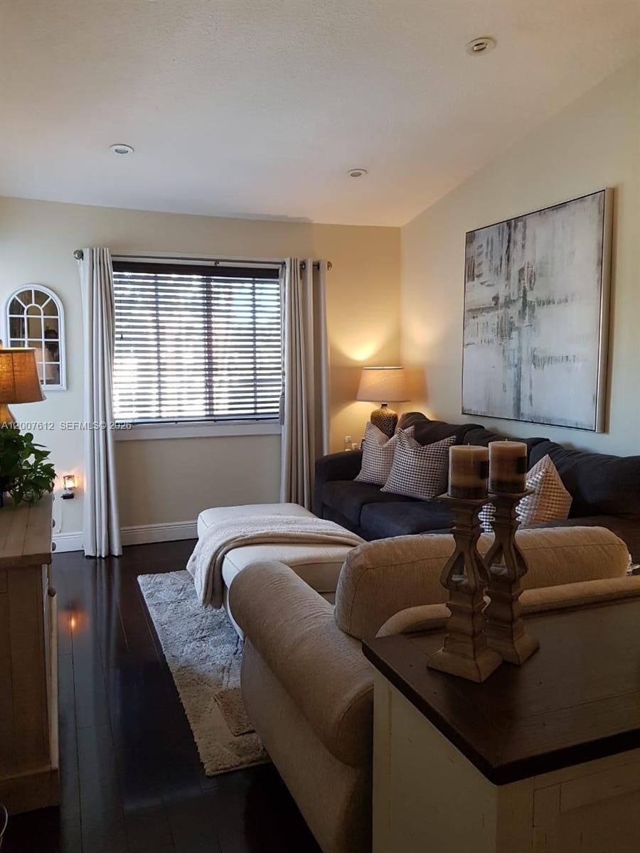 A living room features a dark sofa, a light ottoman, and a large abstract painting — 930 NE 33rd Ter # 202, Homestead FL 33033, HOMESTEAD, FL