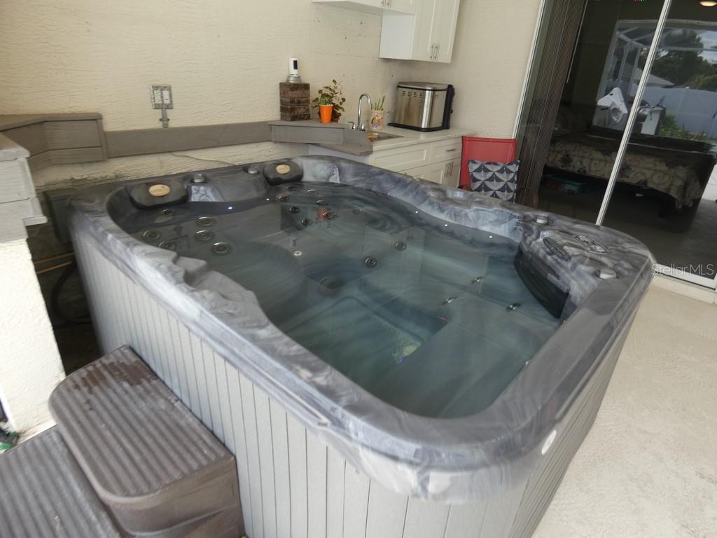 A hot tub sits on a patio next to a small outdoor kitchen area — 8158 WINDING OAK LANE, SPRING HILL, FL