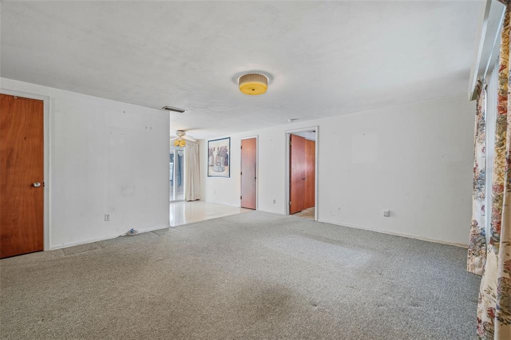 A carpeted living room features white walls, three wooden doors, and a central ceiling light — 4408 W ELM STREET, TAMPA, FL