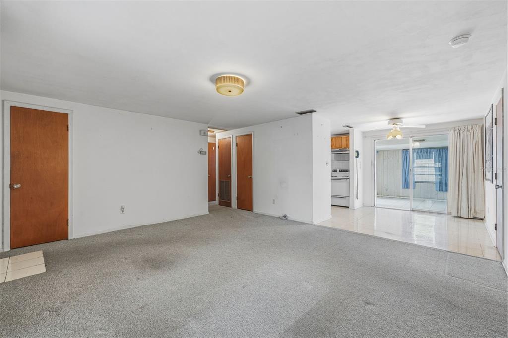 A living room with gray carpeting, white walls, wood doors, and an adjacent tiled area — 4408 W ELM STREET, TAMPA, FL