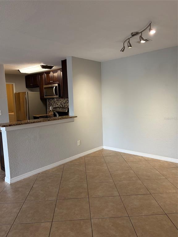 A dining area with tile flooring and a track light fixture overlooks a kitchen — 7511 SEURAT STREET UNIT 10201, ORLANDO, FL