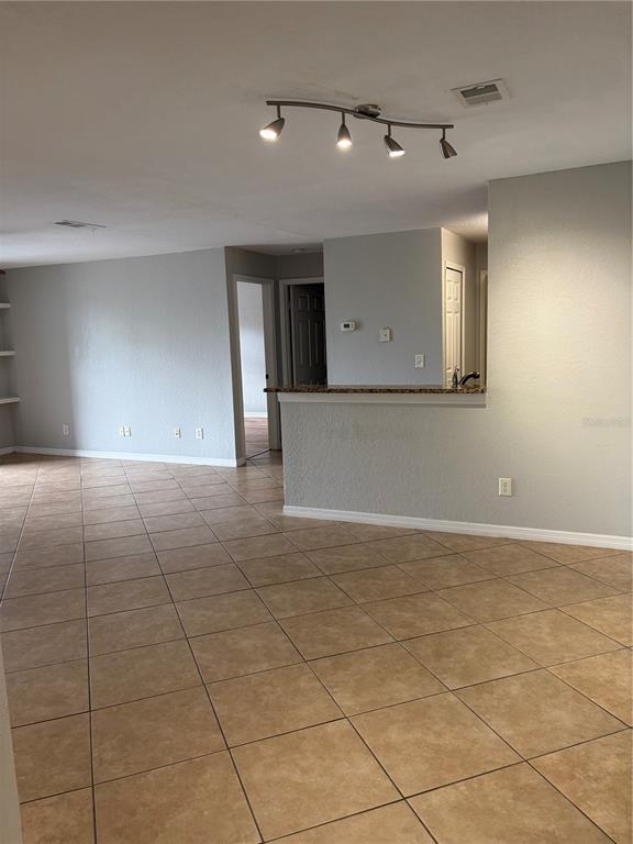 An open-concept living area features light gray walls, tan tile flooring, and a breakfast bar — 7511 SEURAT STREET UNIT 10201, ORLANDO, FL