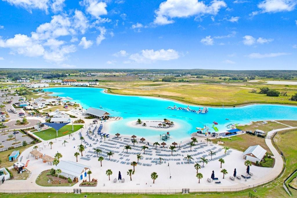 An aerial view of a large turquoise swimming lagoon surrounded by sandy beaches and palm trees — 31426 MANGO FADE WAY, SAN ANTONIO, FL