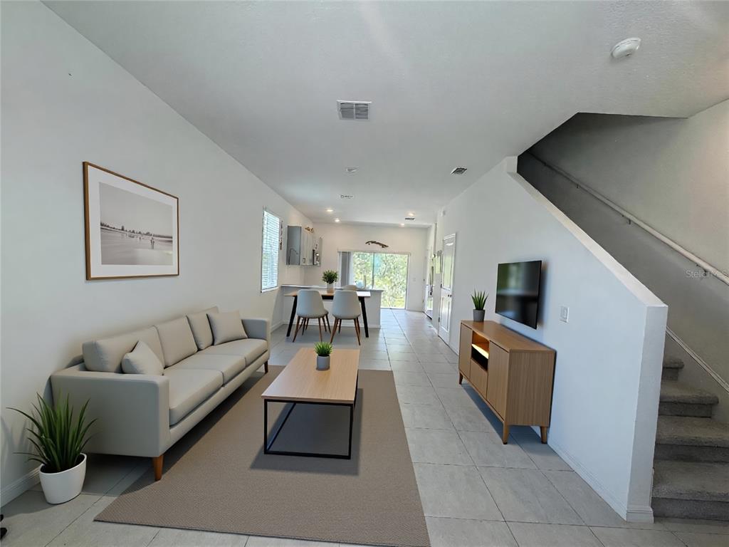 A living room with a grey sofa, coffee table, and television leads to a dining area — 3093 SKYLINE LOOP, KISSIMMEE, FL