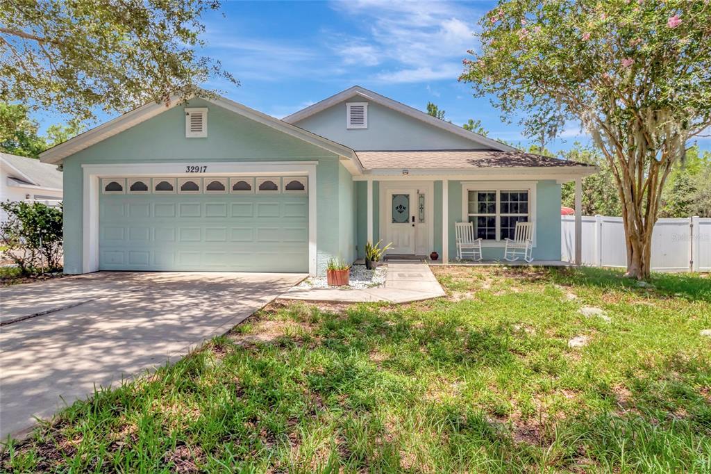 A light blue single-story house features a two-car garage, a front porch, and a lawn — 32917 FOREST AVENUE, LEESBURG, FL
