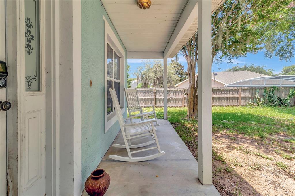 A covered porch with two white rocking chairs sits beside a light blue exterior wall — 32917 FOREST AVENUE, LEESBURG, FL