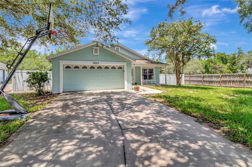 A light blue house with a two-car garage and a basketball hoop in the driveway — 32917 FOREST AVENUE, LEESBURG, FL