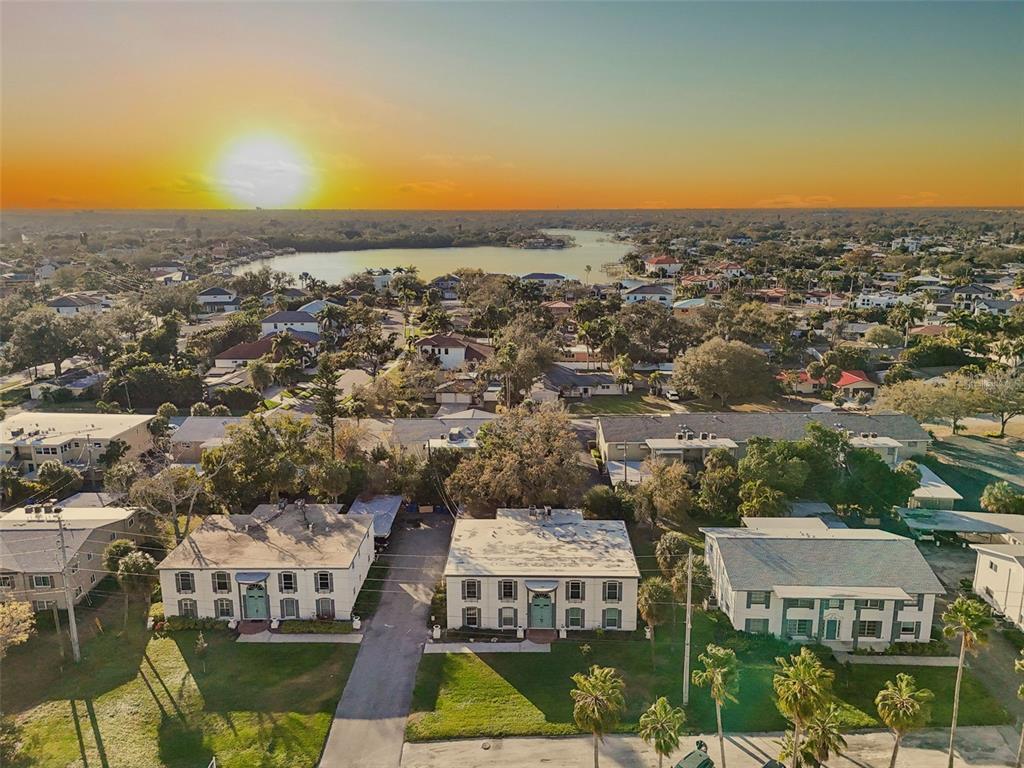 An aerial view shows three apartment buildings with flat roofs near a lake at sunset — 1338 SNELL ISLE BOULEVARD NE UNIT 2, ST PETERSBURG, FL