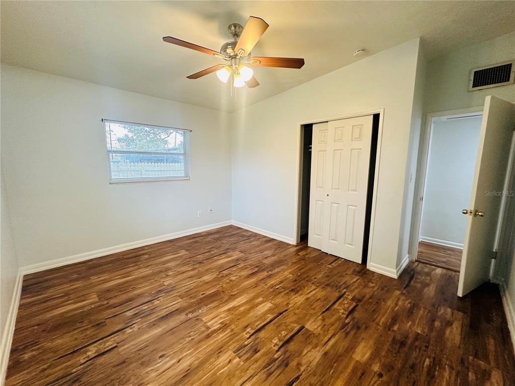 A bedroom with light-colored walls, a ceiling fan, a closet, and wood-look flooring — 6033 BALBOA DRIVE, ORLANDO, FL