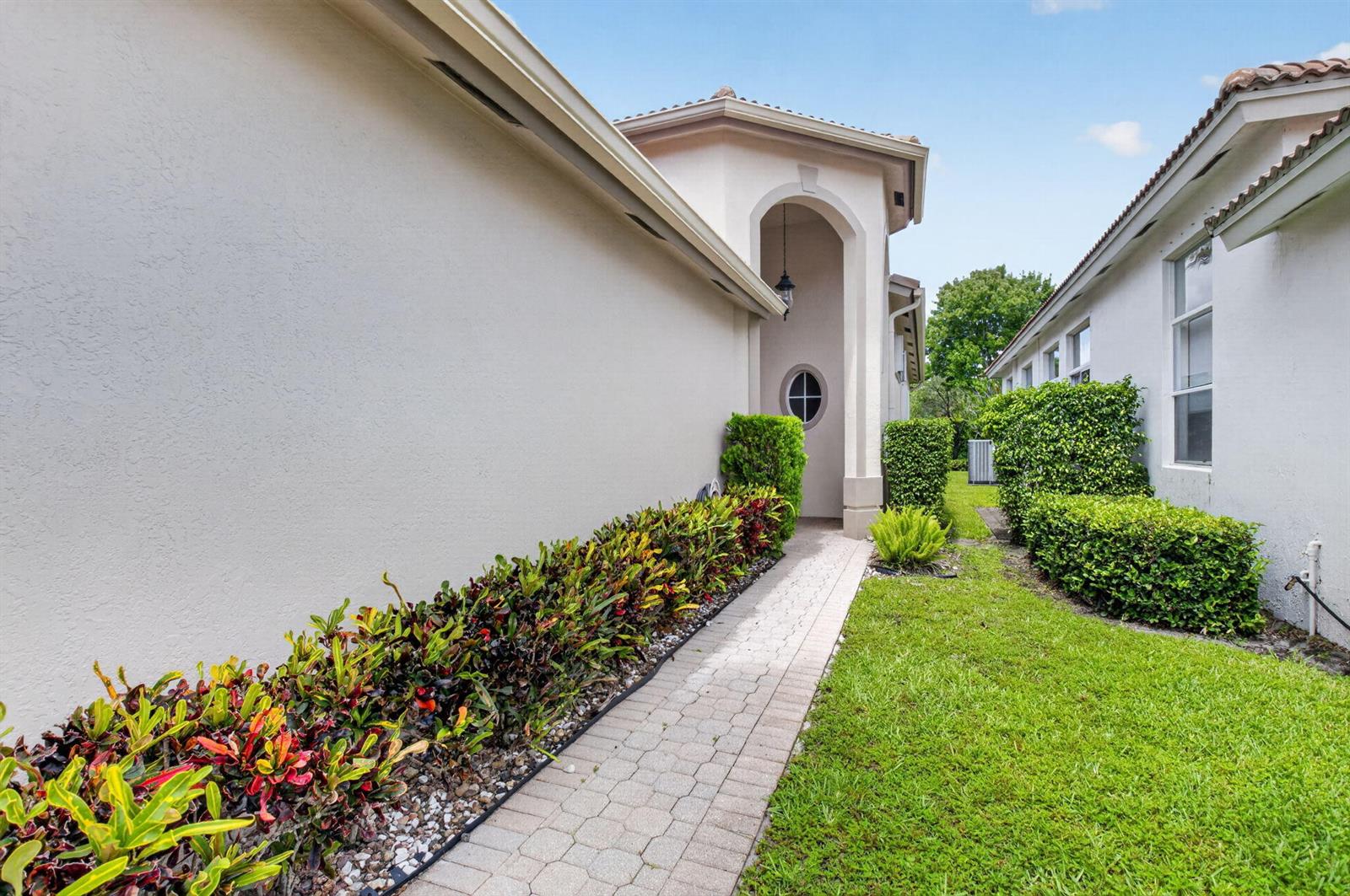 A paved walkway leads between two stucco houses with manicured hedges and a small lawn — 11585 Green Golf Lane, Boynton Beach FL 33437, BOYNTON BEACH, FL