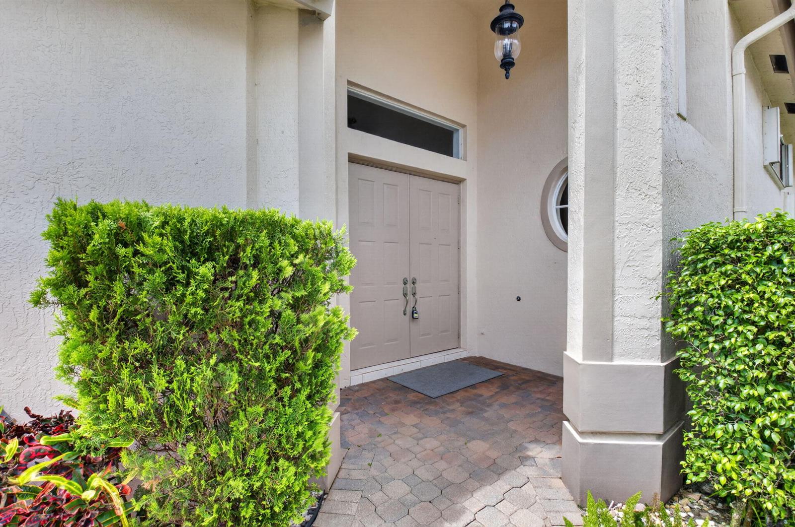 A beige double front door with a transom window sits under a covered entryway — 11585 Green Golf Lane, Boynton Beach FL 33437, BOYNTON BEACH, FL