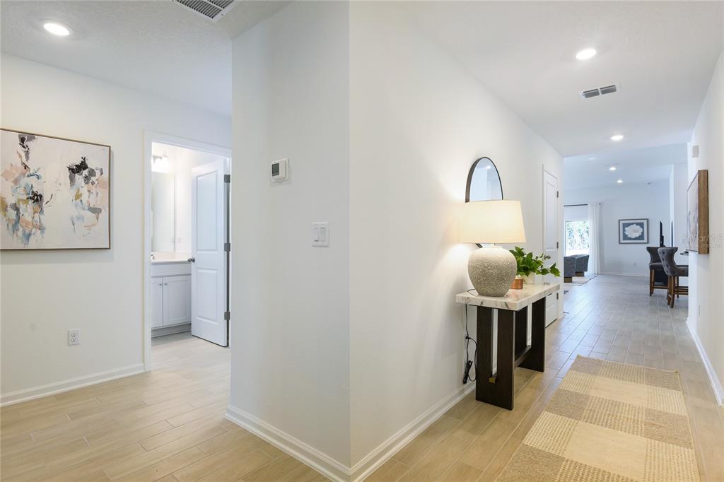 A bright hallway features light tile flooring, a console table with a lamp, and wall art — 3445 GOLDEN EYE DRIVE, ORANGE PARK, FL