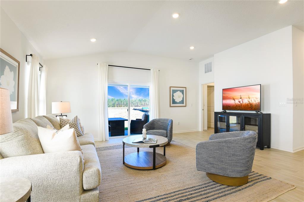 A bright living room features a sofa, two armchairs, a coffee table, and sliding glass doors — 3445 GOLDEN EYE DRIVE, ORANGE PARK, FL