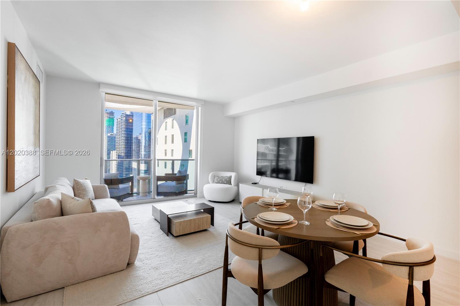 A modern living and dining area features a sofa, round table, and floor-to-ceiling windows — 77 SE 5th St # 3914, Miami FL 33131, MIAMI, FL