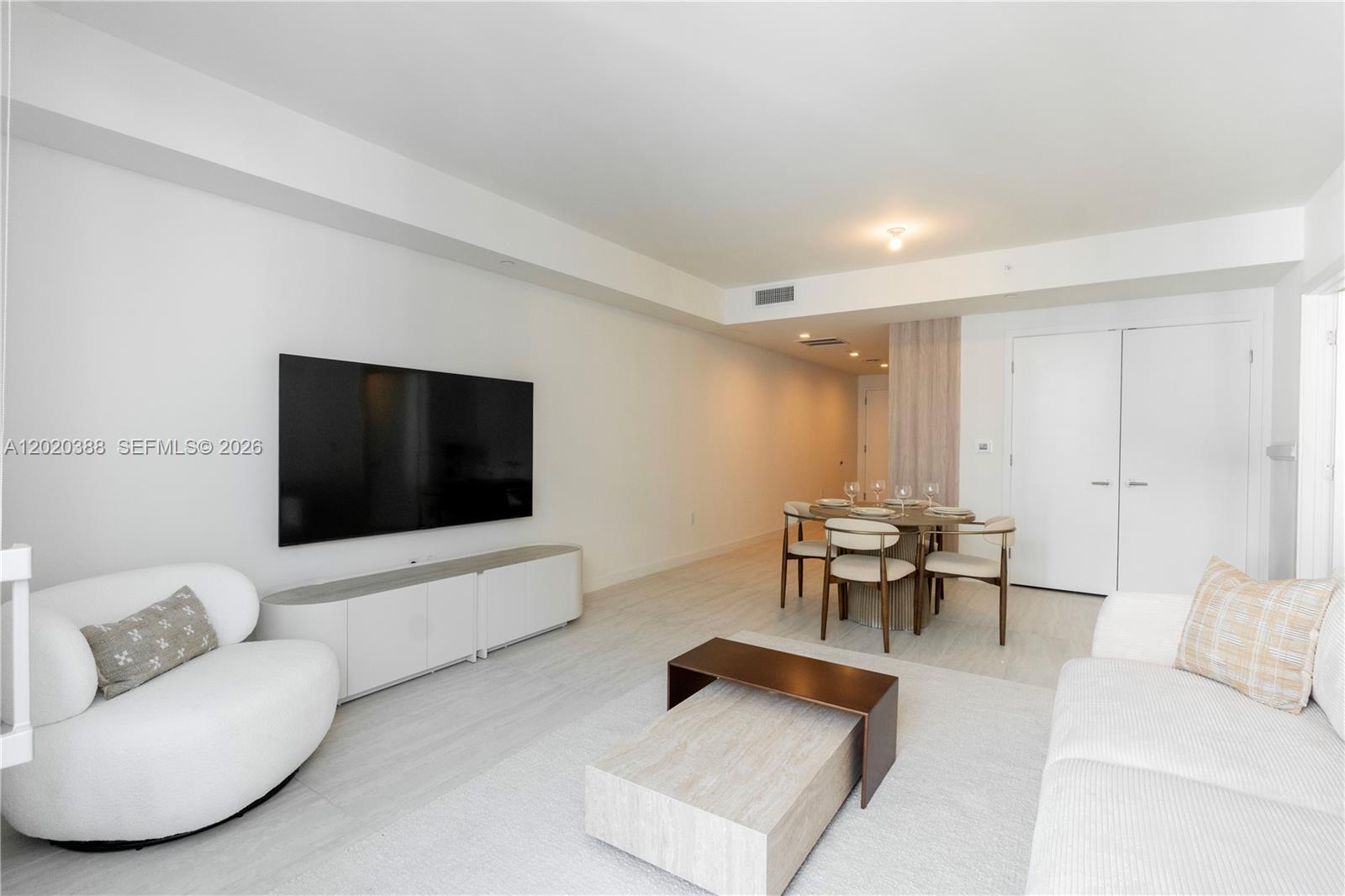 A modern living and dining area features white walls, light flooring, and minimalist furniture — 77 SE 5th St # 3914, Miami FL 33131, MIAMI, FL