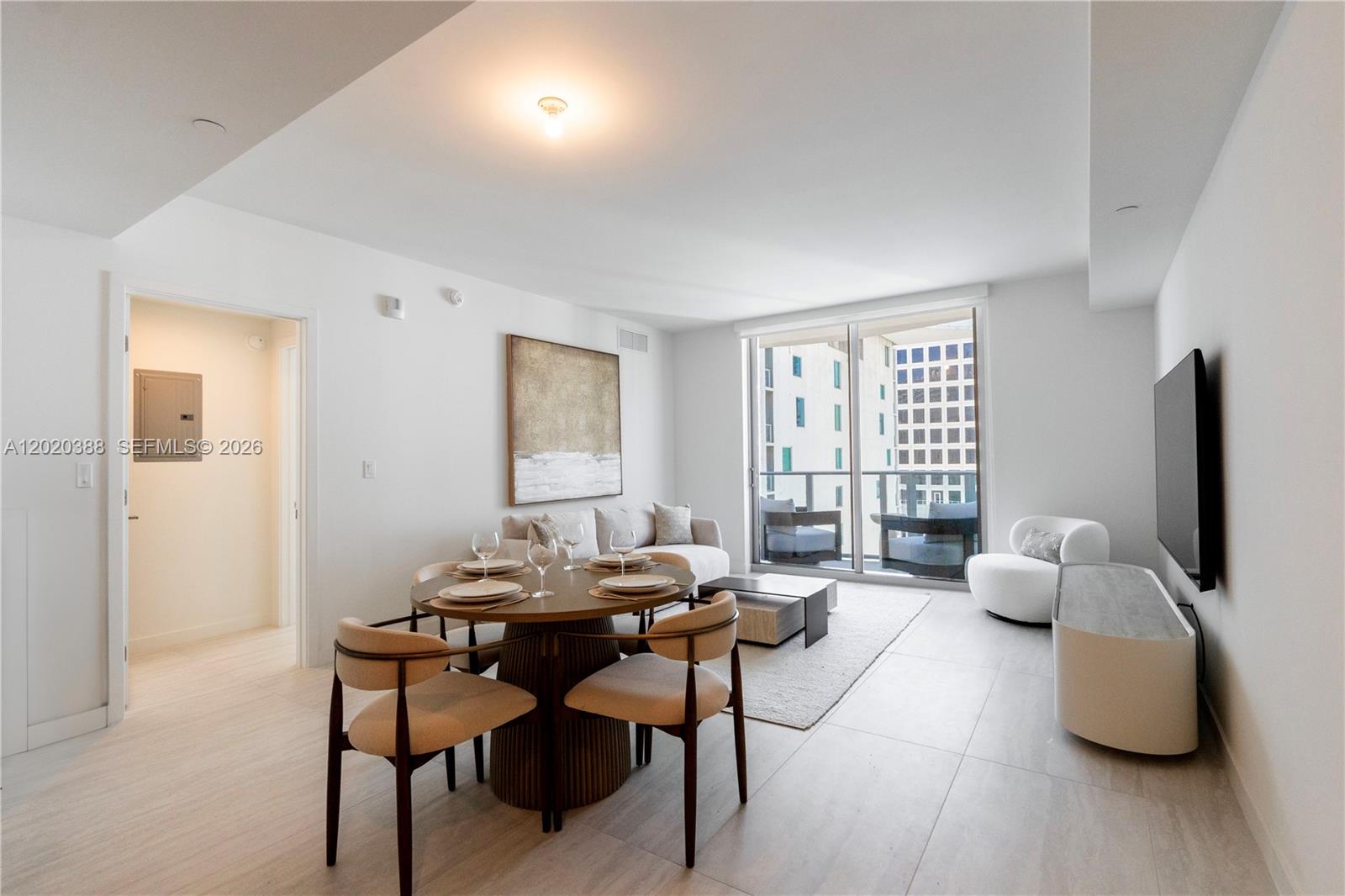 A modern living and dining area features a round table, sofa, and floor-to-ceiling windows — 77 SE 5th St # 3914, Miami FL 33131, MIAMI, FL