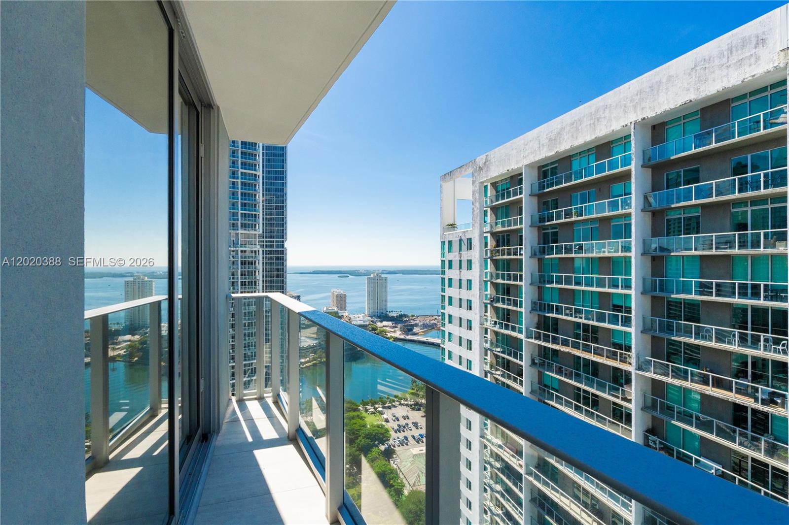 A balcony with a glass railing overlooks a bay and nearby high-rise buildings — 77 SE 5th St # 3914, Miami FL 33131, MIAMI, FL