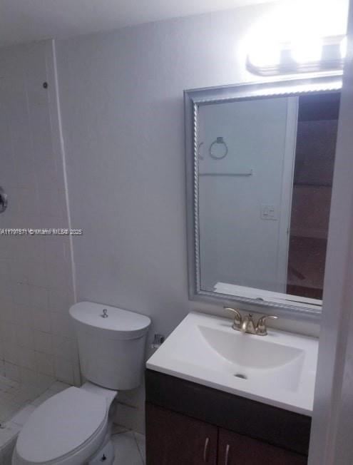 A bathroom featuring a white toilet, a dark wood vanity with a sink, and a mirror — 15600 NW 7th Ave # 319, Miami FL 33169, MIAMI, FL